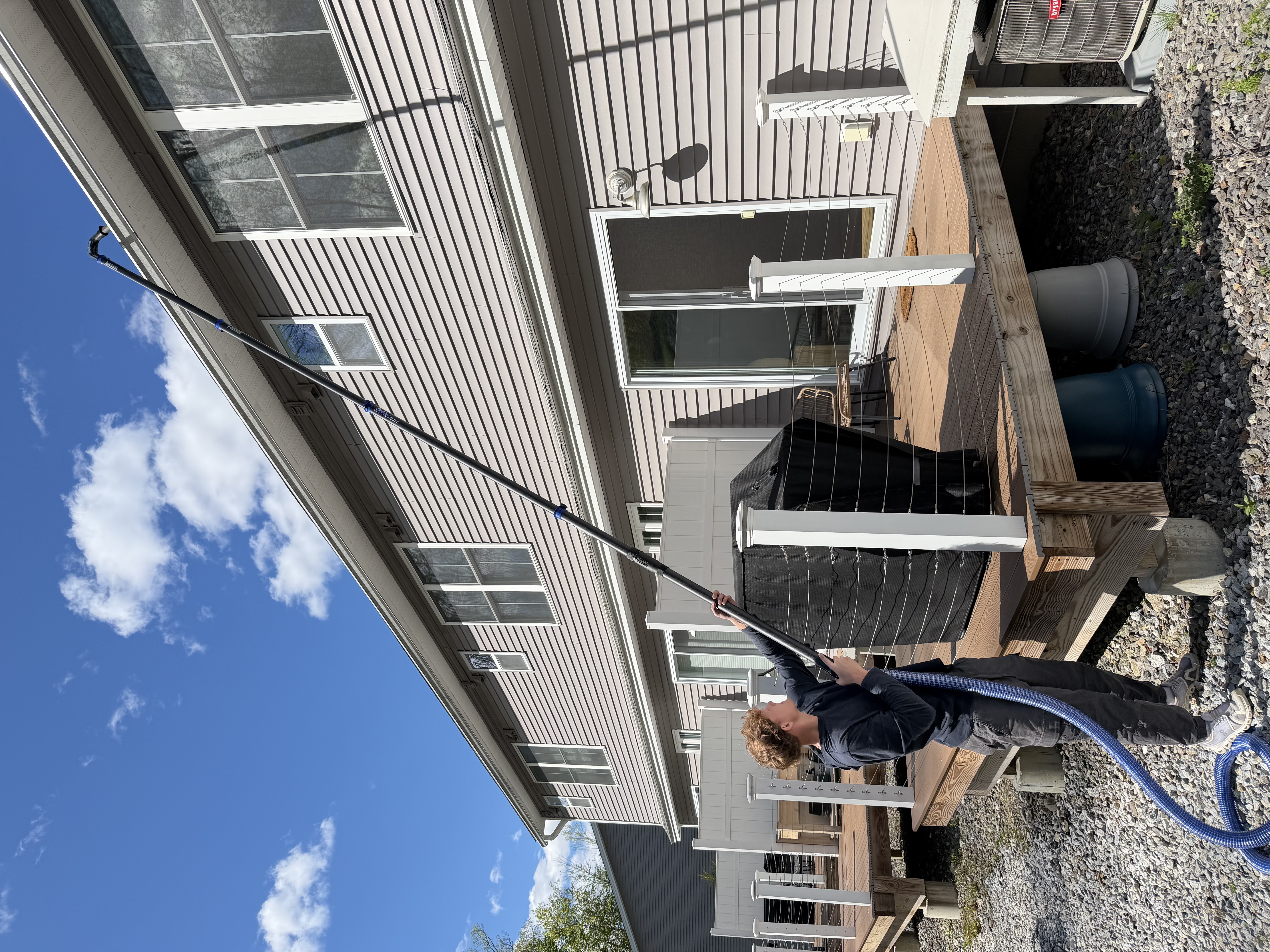 Operator cleaning gutters from the ground with high-reach pole